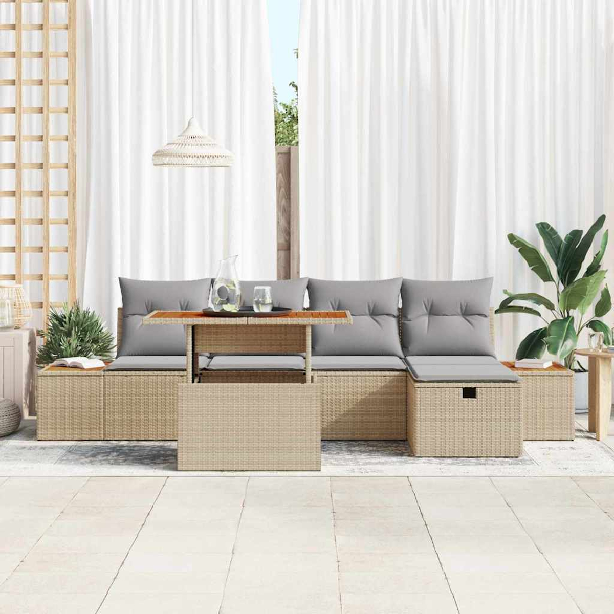 Rattansofa-Set im Freien mit grauen Kissen, einem Tisch mit Glaskaraffe und einer großen Pflanze. Weiße Vorhänge im Hintergrund.