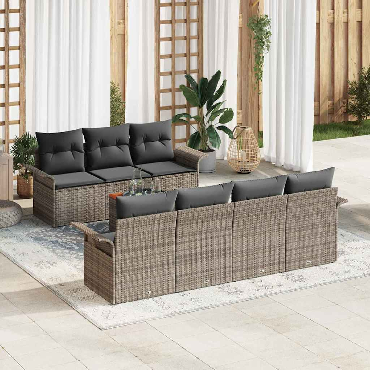 Outdoor-Terrassenset mit grauen Kissen. Zwei Korbs Sofas und ein Teppich stehen vor weißen Vorhängen und Holzstrukturen.