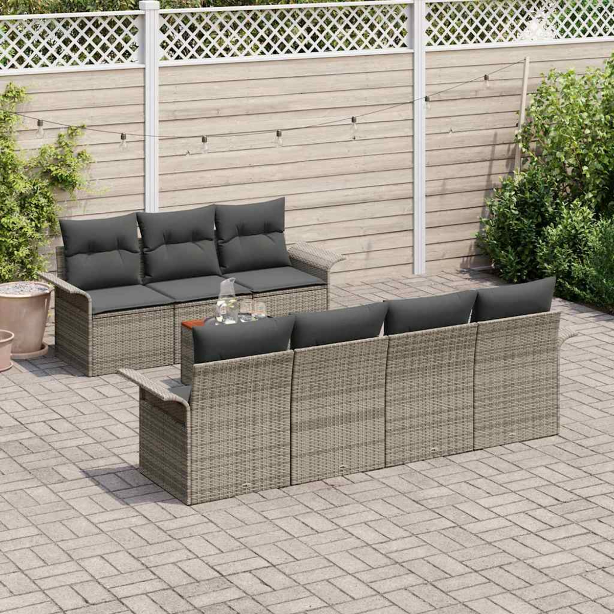 Gartenmöbel-Set. Zwei Korbs Sofas mit grauen Kissen. Ein Holztisch mit Krug und Gläsern. Ziegel-Terrasse.