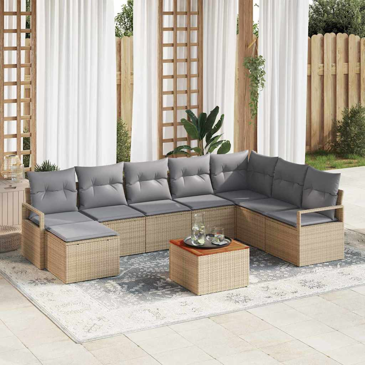 Outdoor-Ecksofa mit grauen Kissen, einem Holztisch und einem gemusterten Teppich auf einer Terrasse. Weiße Vorhänge im Hintergrund.
