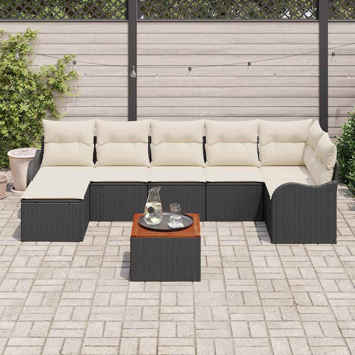 Outdoor-Ecksofa mit cremefarbenen Kissen, kleinem Tisch mit Glas, Terrasse und Zaun.