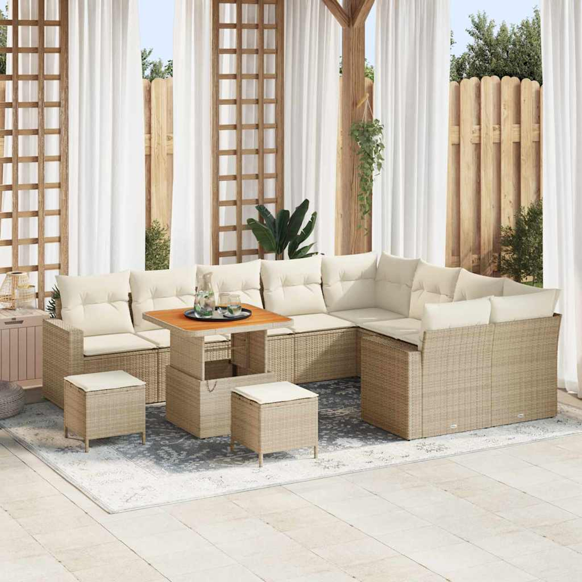 Garten-Wohnset mit beigen Kissen. Enthält ein Ecksofa, einen Tisch und Hocker, auf einem gemusterten Teppich.