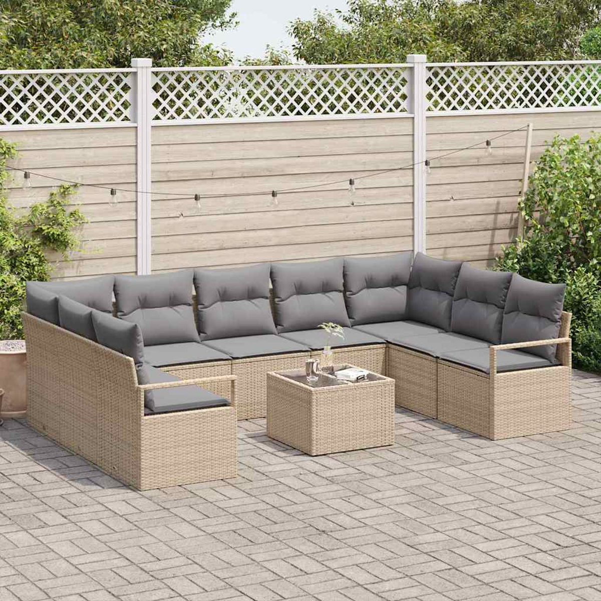 Ein Ecksofa mit grauen Kissen und einem kleinen Tisch im Freien. Ein weißer Zaun und Grün im Hintergrund.