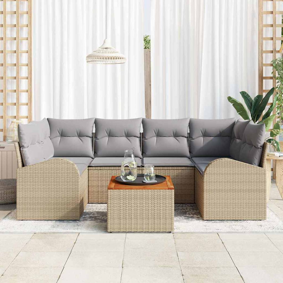 Geflochtenes Ecksofa mit grauen Kissen und einem Couchtisch aus Holz. Weiße Vorhänge und eine Pendelleuchte sind im Hintergrund zu sehen.