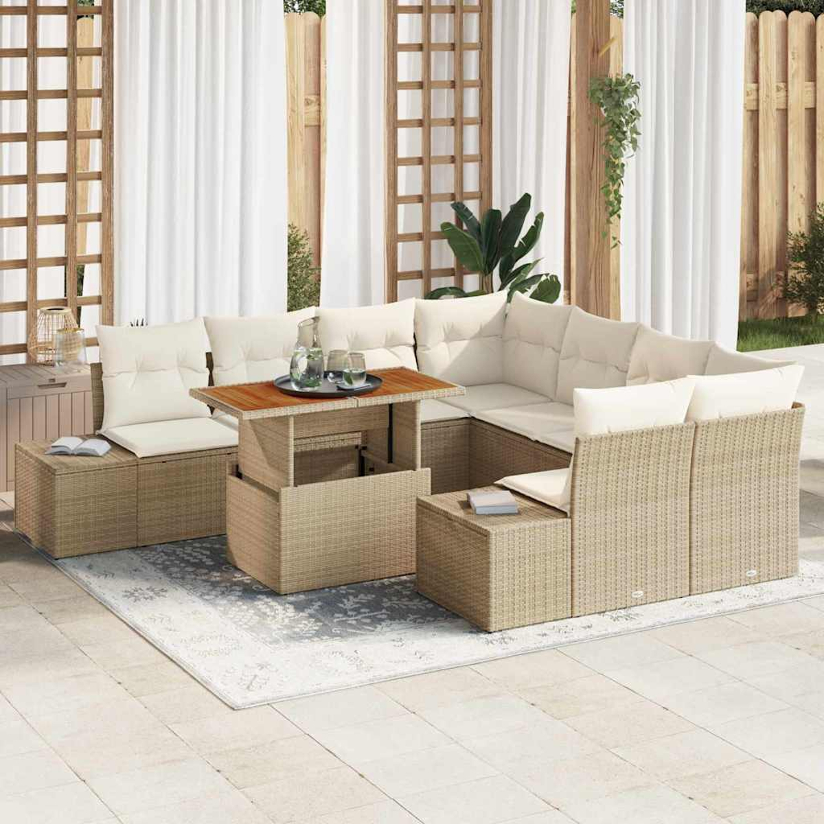 Terrassenmöbel-Set mit beigefarbenen Korbmöbeln, weißen Kissen und einem Holztisch auf einem grauen Teppich. Weiße Vorhänge im Hintergrund.