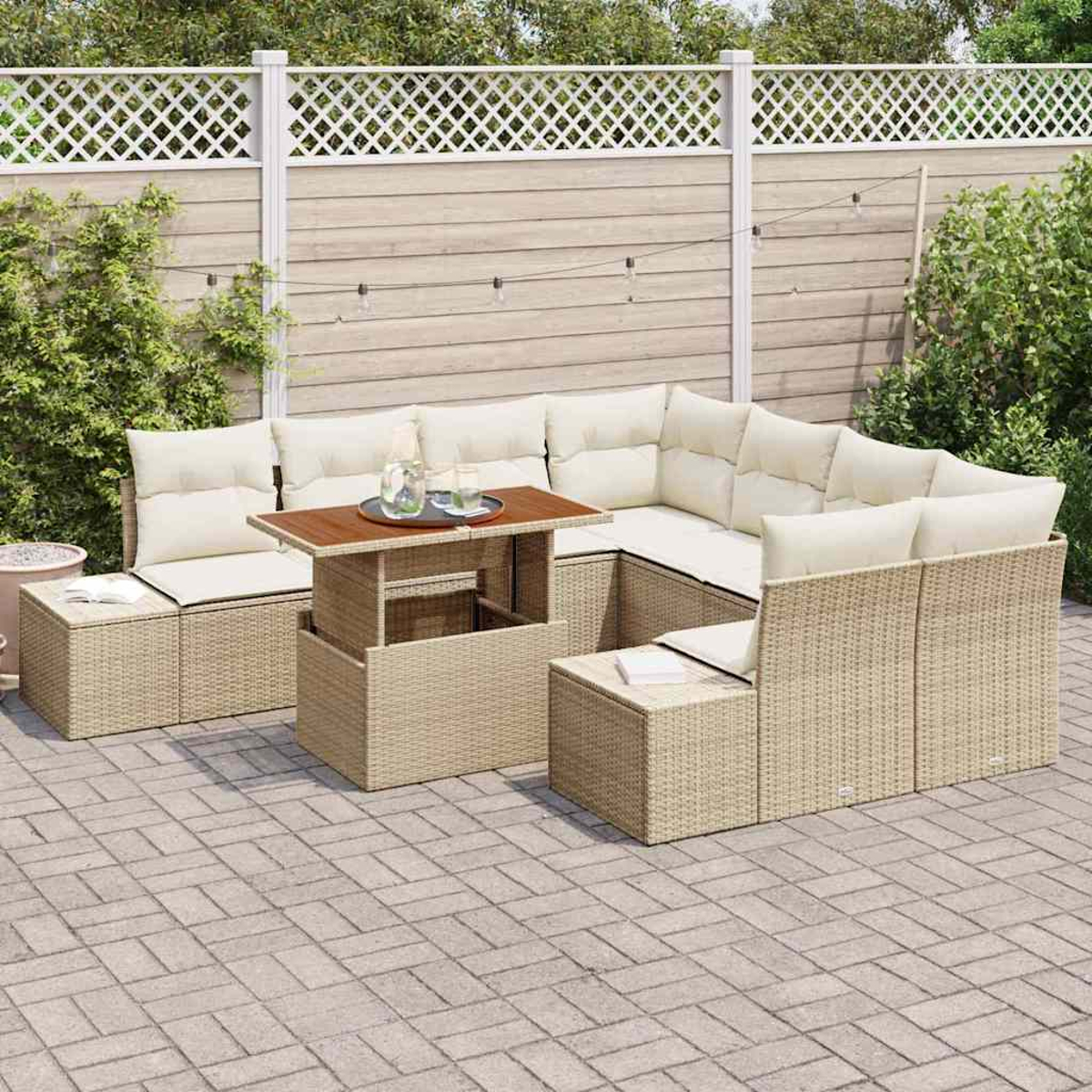 Garten-Wicker-Sofagarnitur mit Kissen und einem Couchtisch auf einer Backstein-Terrasse. Ein weißer Zaun und Grün im Hintergrund.