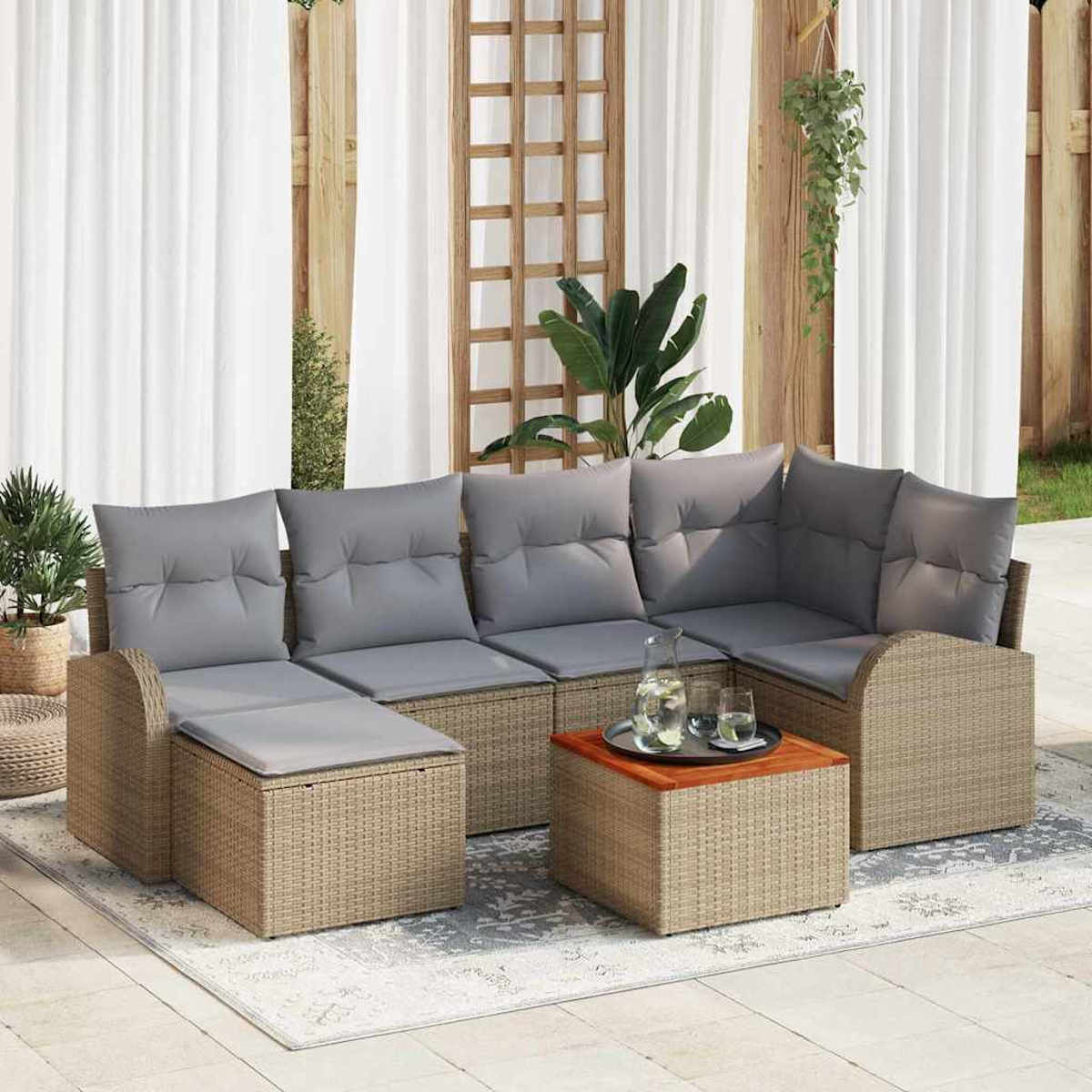 Juego de asientos al aire libre con cojines grises, mesa auxiliar de madera y plantas. Sobre una alfombra, con cortinas y celosía de madera.