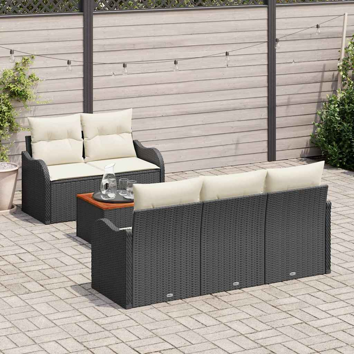 Gartenmöbel-Set: graues Korbmöbelsofa und -liege mit cremefarbenen Kissen, kleiner Tisch mit Gläsern, Lichterkette und Holzzaun.