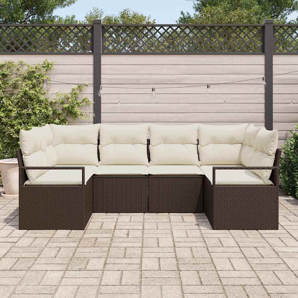 Ein Ecksofa im Freien mit cremefarbenen Kissen steht auf einer Ziegelterrasse. Im Hintergrund befinden sich ein Holzzaun und Grün.