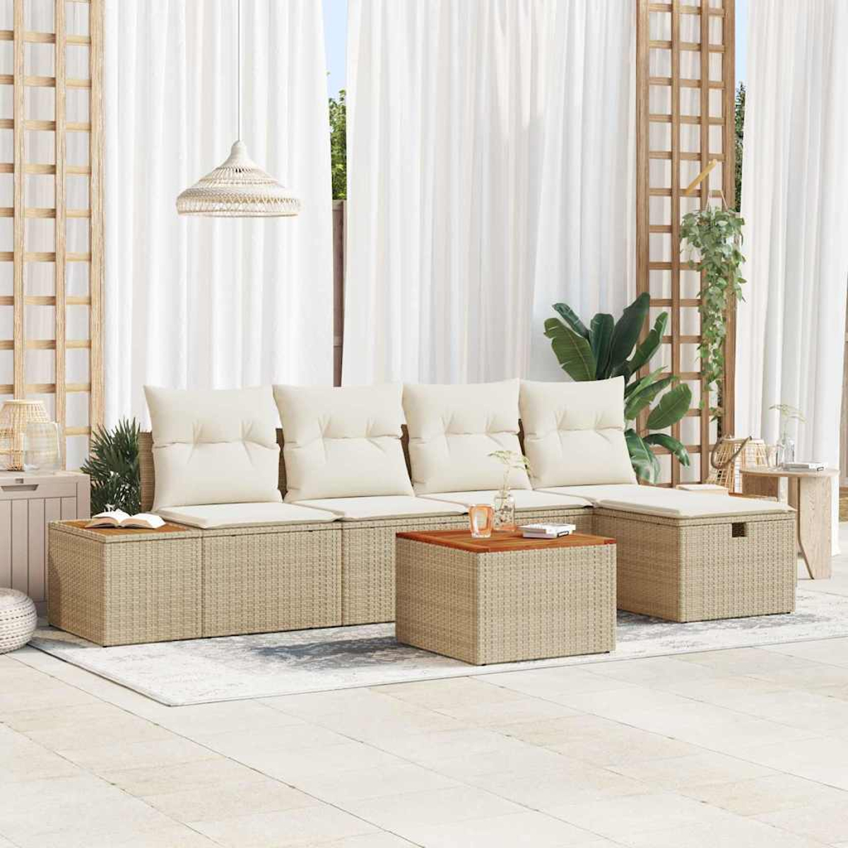 Outdoor-Sitzbereich mit beigen Korbmöbeln, weißen Kissen und einem Holztisch. Weiße Vorhänge und Pflanzen im Hintergrund.