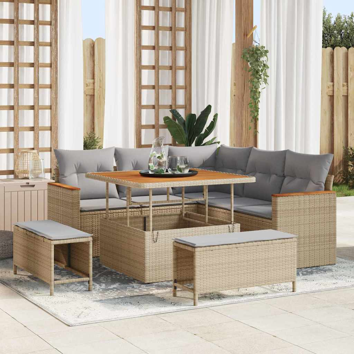 Gartenmöbel-Set aus Korbgeflecht mit grauen Kissen, Holztisch mit Gläsern und Wasser sowie zwei Bänken auf einem Teppich.