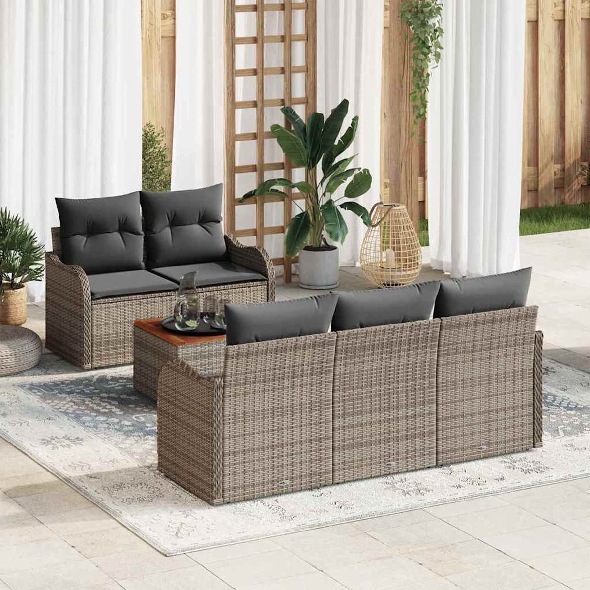 Garten-Terrassenset mit grauen Kissen. Enthält ein Loveseat, Sofa und Couchtisch auf einem gemusterten Teppich, in der Nähe von Pflanzen und weißen Vorhängen.