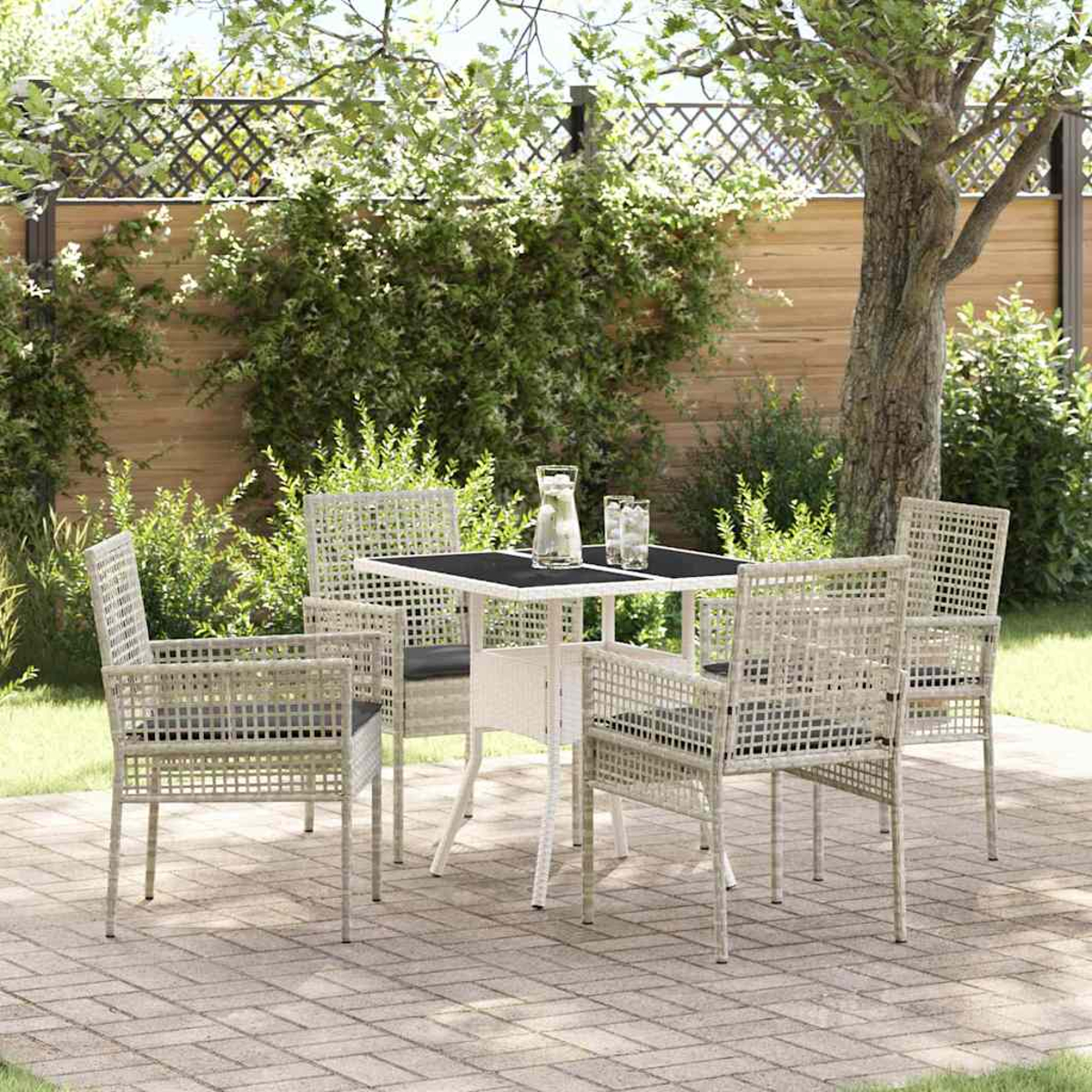 Garten-Terrassenset mit quadratischem Tisch und vier Stühlen, Getränke auf dem Tisch. Ziegelpflaster, grüne Pflanzen und Bäume im Hintergrund.