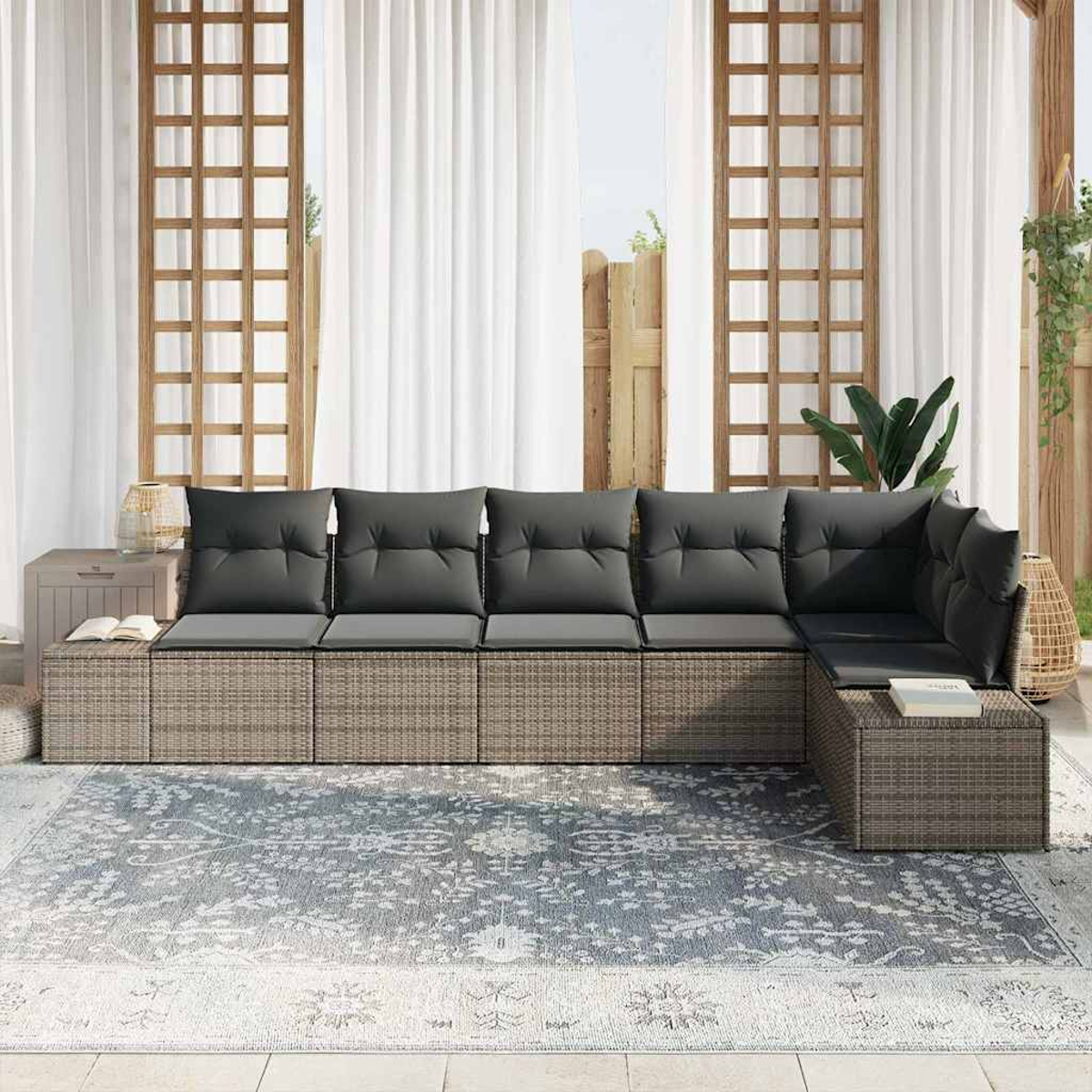 Gartensofa mit grauen Kissen und grauem Teppich. Weiße Vorhänge und Holzgitter im Hintergrund.