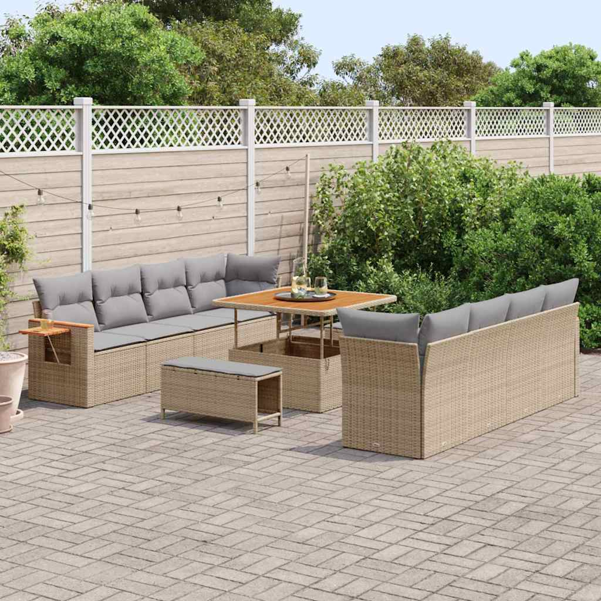 Terrassengarnitur im Freien mit Tisch, Bänken und Sofas, umgeben von einem Zaun, Grün und Pflastersteinen.