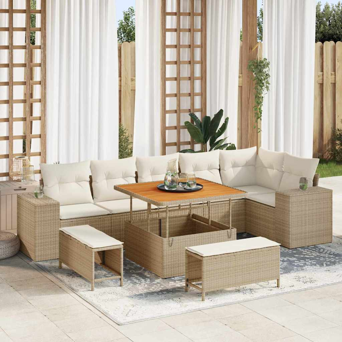 Set di mobili in vimini da esterno. Include un divano, un tavolo e panche. Cuscini beige e un tavolo in legno, su un tappeto. Tende sullo sfondo.