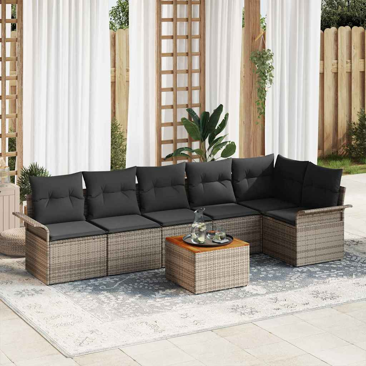 Outdoor-Ecksofa mit grauen Kissen, Holztisch mit Tablett und gemustertem Teppich auf einer Terrasse.