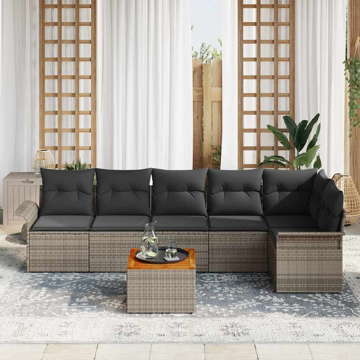 Outdoor-Sitzgruppe mit grauen Kissen. Enthält einen Couchtisch mit Tablett und Glas. Der Hintergrund hat Vorhänge und Holzgitter.