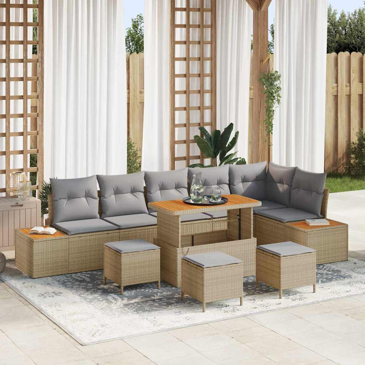 Terrassenset mit beigen Korbmöbeln, grauen Kissen, einem Holztisch und Hockern auf einem gemusterten Teppich, mit weißen Vorhängen.