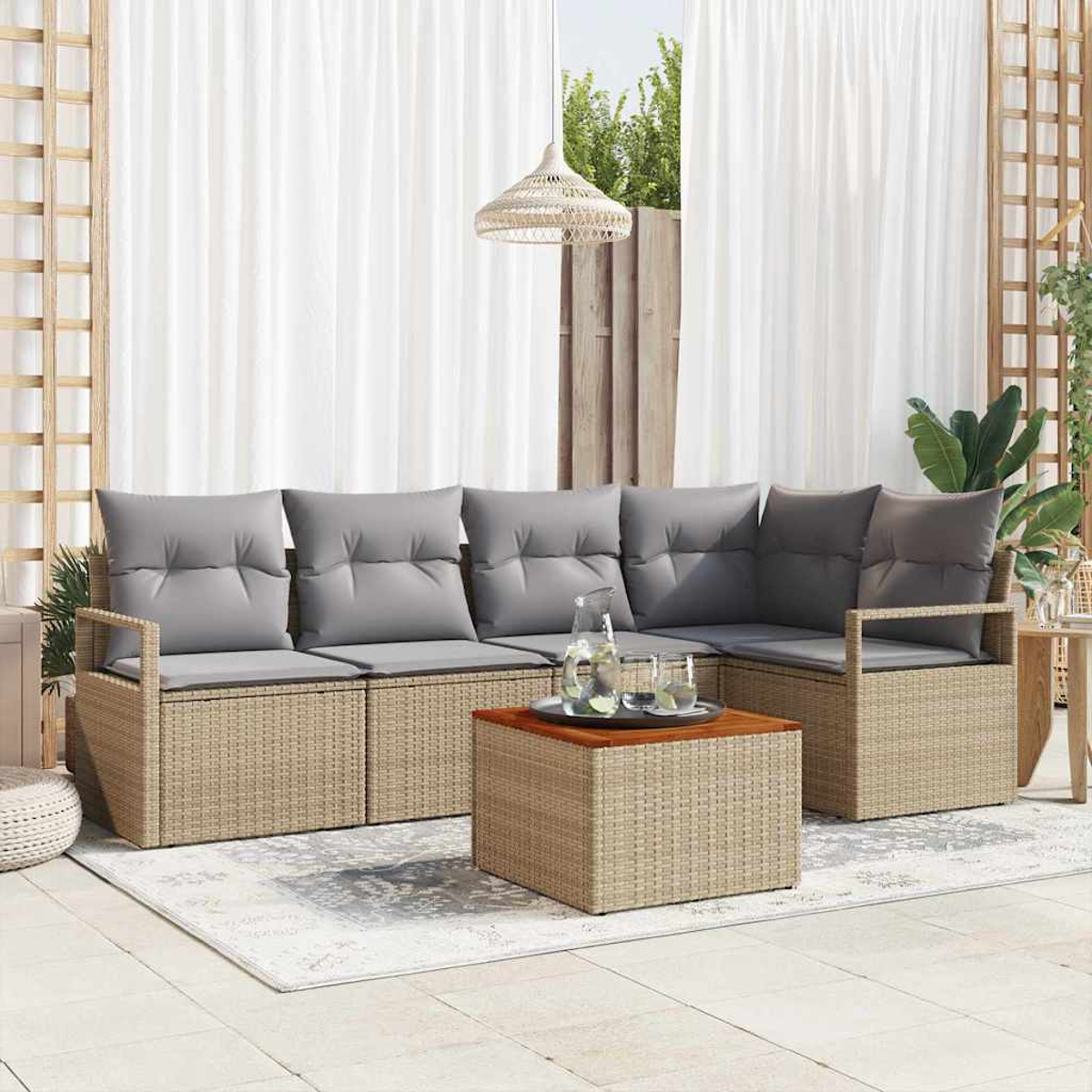 Outdoor-Korbsessel mit grauen Kissen und einem Holztisch. Weiße Vorhänge im Hintergrund, mit Pflanzen und einer Hängelampe.