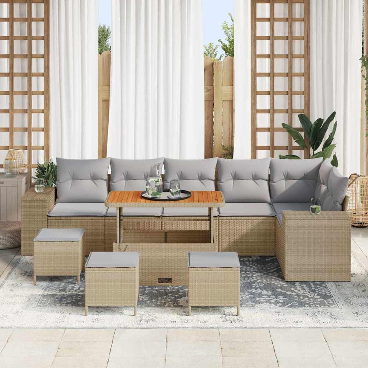 Outdoor-Ecksofa mit grauen Kissen, Holztisch und passenden Hockern auf einem Teppich. Weiße Vorhänge und Holzzaun im Hintergrund.