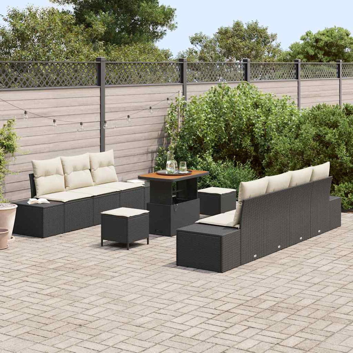 Garten-Terrassenset. Enthält ein dunkelgraues Sofa, Ottomanen und einen Tisch. Ein Holzzaun und Grün sind im Hintergrund zu sehen.