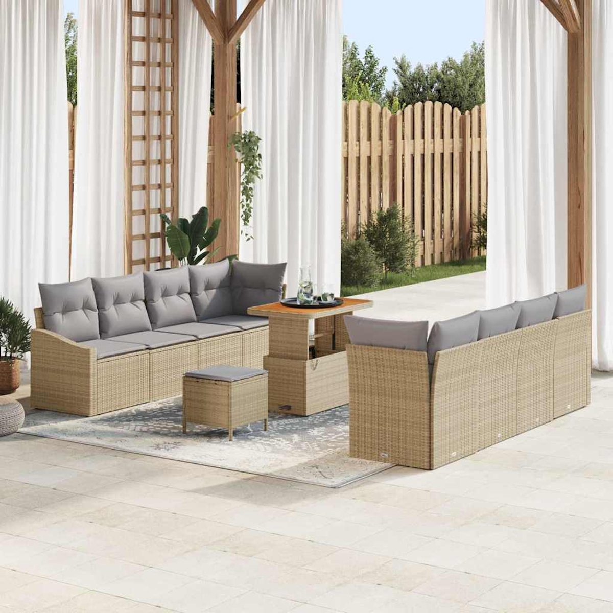 Gartenmöbel-Set. Enthält Sofas mit grauen Kissen, einen Tisch und eine Ottomane. Weiße Vorhänge und Holzzaun im Hintergrund.