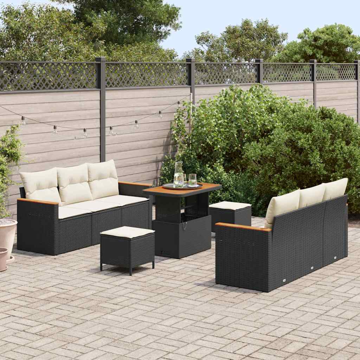 Garten-Terrassenset auf einer Ziegelterrasse. Enthält ein Sofa, zwei Stühle, einen Tisch und zwei Hocker. Ein Zaun und Grünzeug sind im Hintergrund.