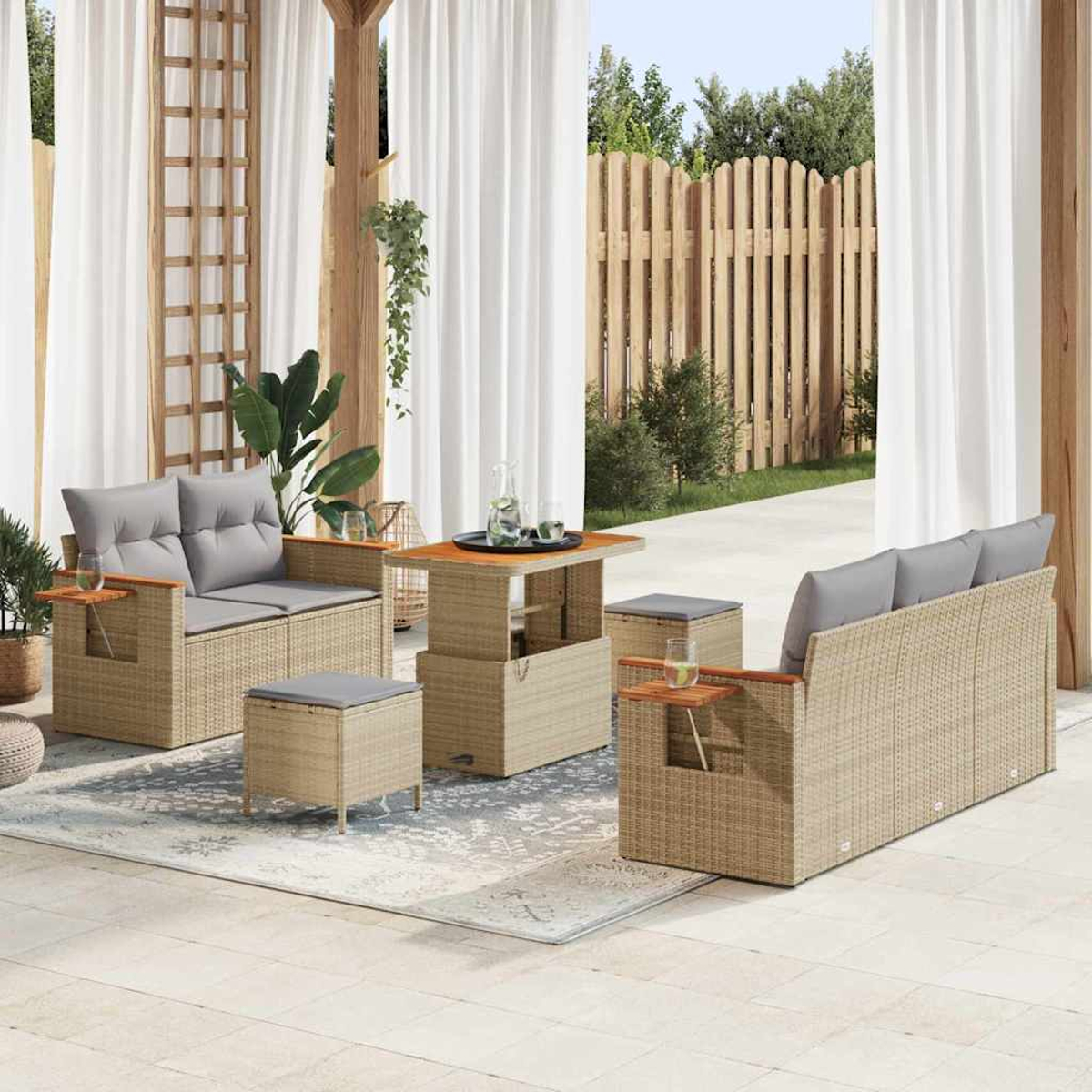 Wohnzimmerset für draußen. Beige Korbmöbel mit grauen Kissen, einem Tisch und Hockern. Holzzaun und weiße Vorhänge im Hintergrund.