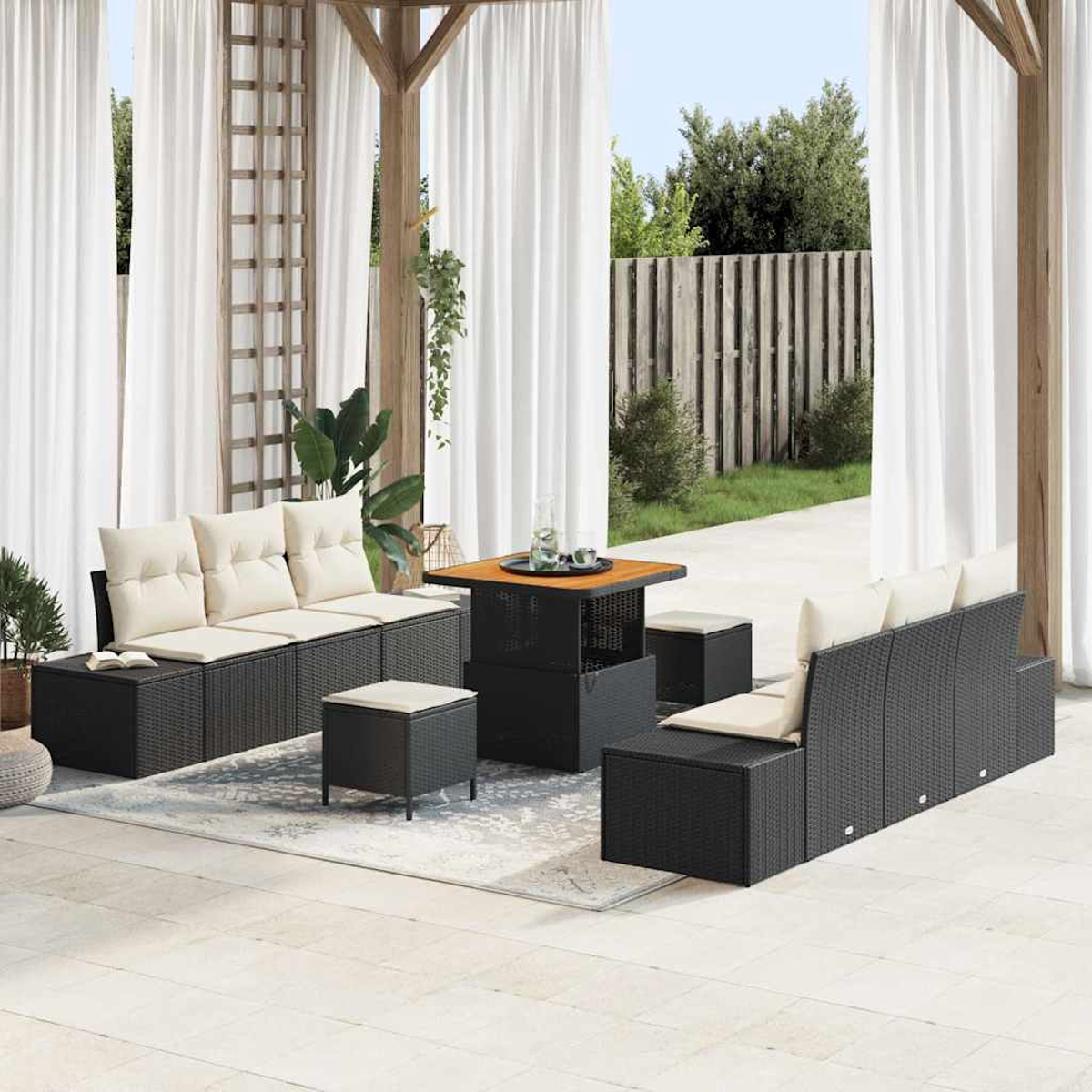Terrassenset mit schwarzem Korbmöbel, beigen Kissen, einem quadratischen Tisch und weißen Vorhängen im Hintergrund.