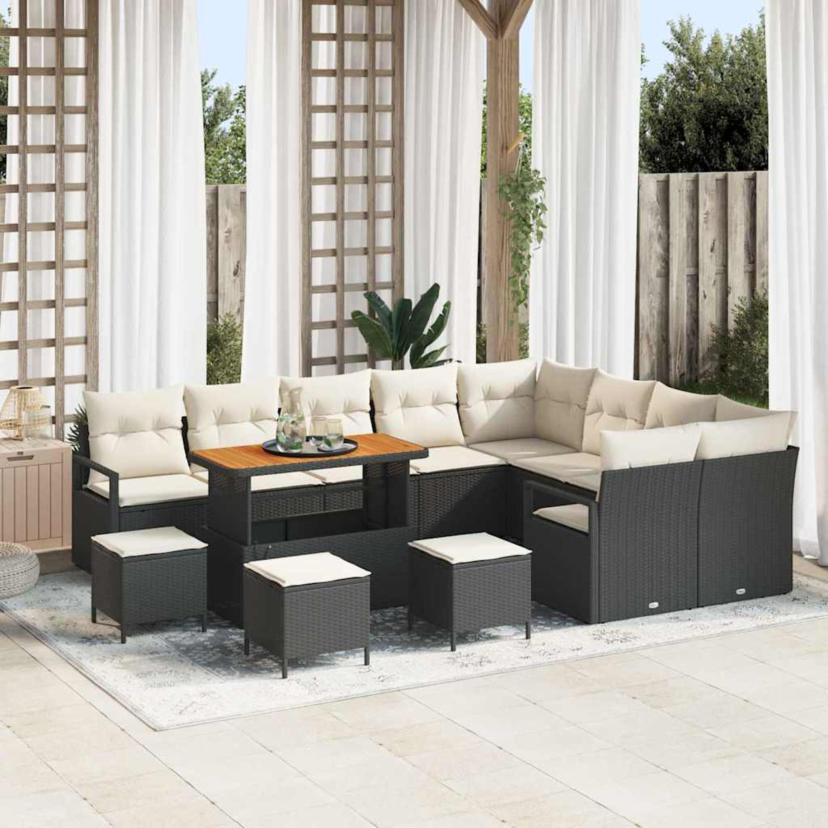 Gartenmöbel-Set auf einer Terrasse. Enthält ein Sofa, einen Tisch und Hocker. Weiße Vorhänge und Holzgitter im Hintergrund.