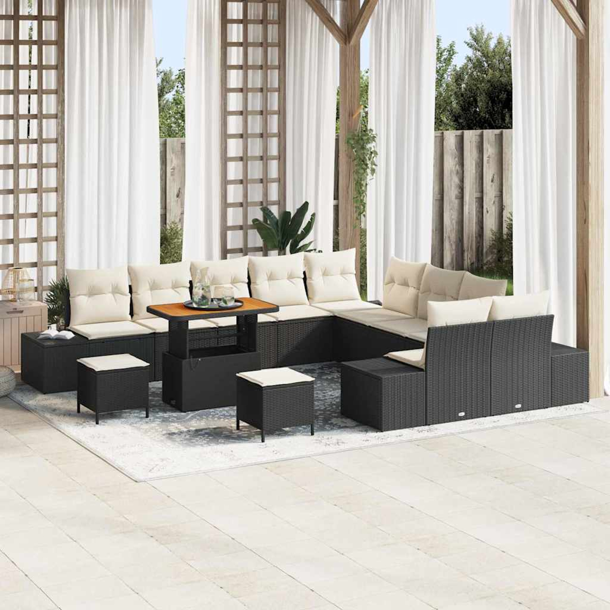 Outdoor-Terrassenset mit schwarzen Korbmöbeln, cremefarbenen Kissen und einem Holztisch. Weiße Vorhänge und ein heller Teppich sind ebenfalls vorhanden.