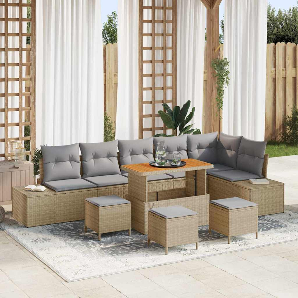 Gartenmöbel-Set aus Rattan mit grauen Kissen, einem Tisch mit Gläsern und weißen Vorhängen im Hintergrund.