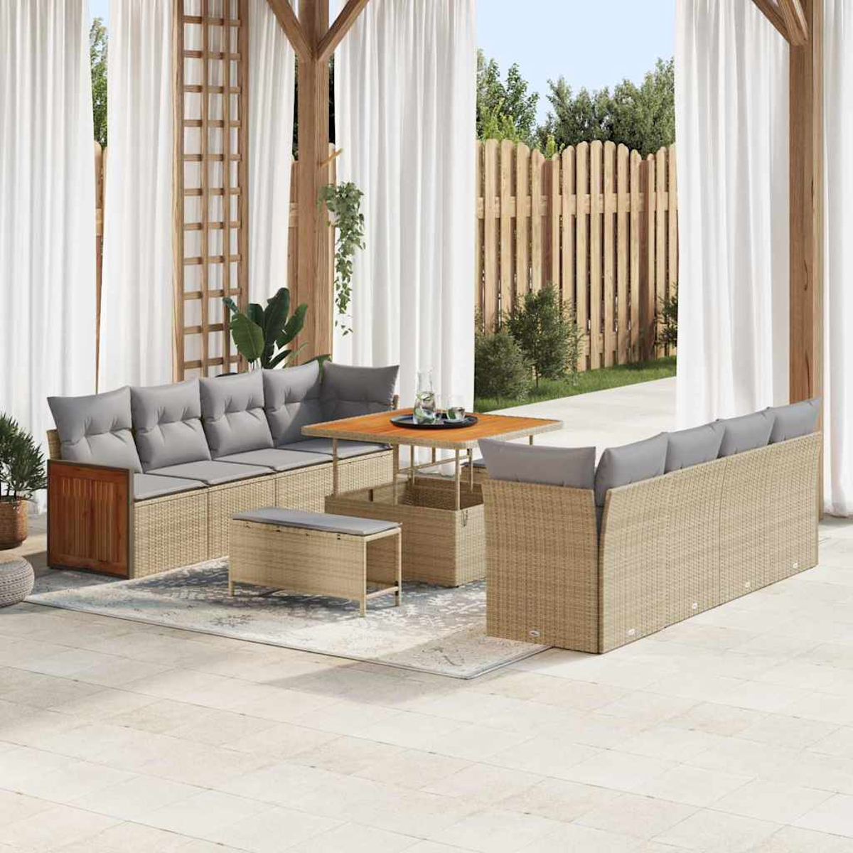 Terrassenset: Sofa, Tisch, Bank und Stauraum aus Korbgeflecht. Weiße Vorhänge, Holzstruktur und Holzzaun im Hintergrund.