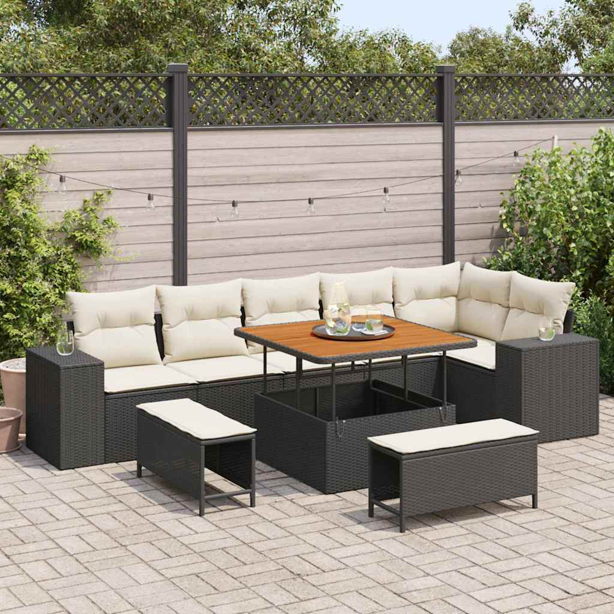 Outdoor-Terrassenset mit Ecksofa, Couchtisch und Bänken. Beige Kissen, dunkelgraues Korbgeflecht und Tischplatte aus Holz. Gartenhintergrund.