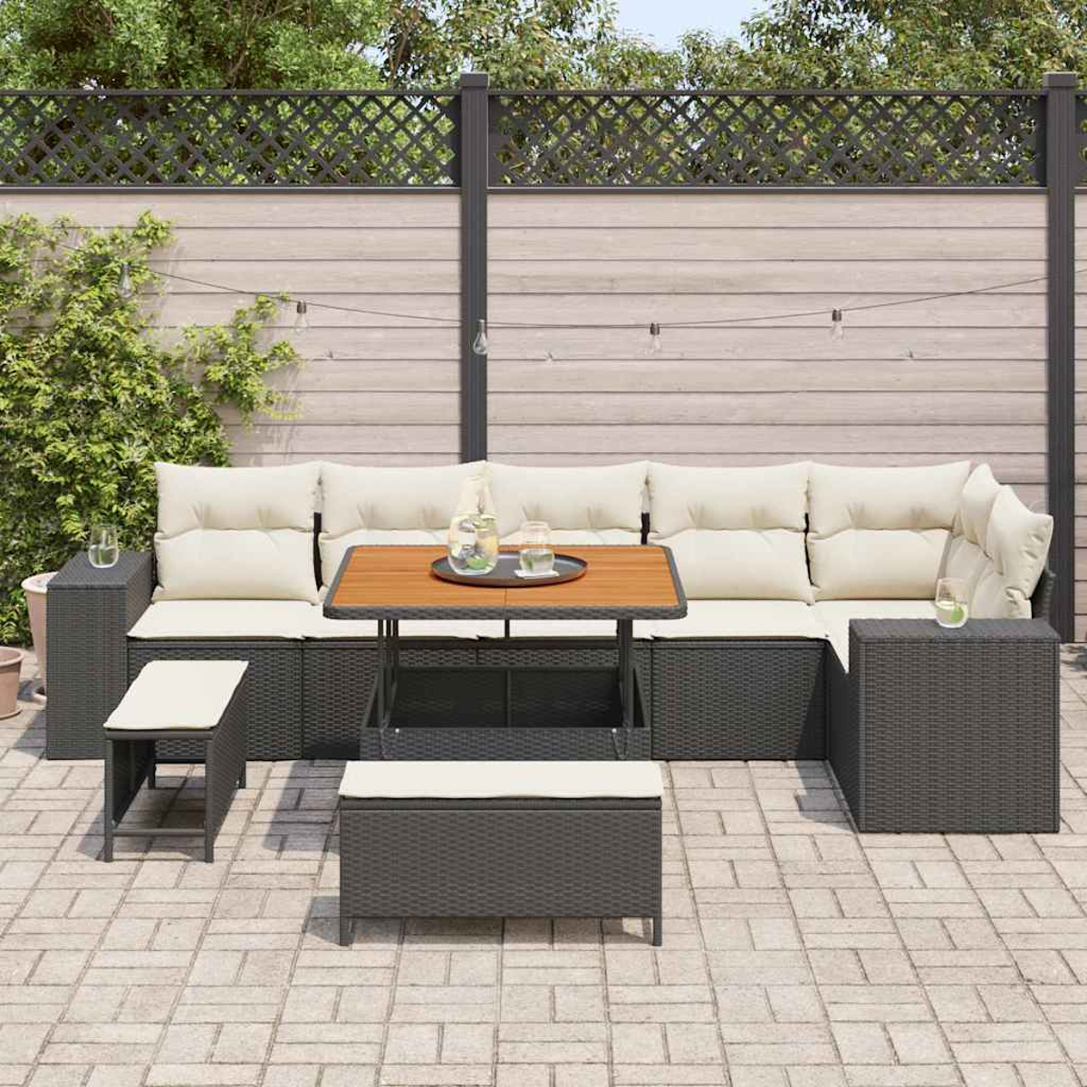 Terrassenset mit grauem Sofa, Holztisch und kleiner Bank. Weiße Kissen, Gläser und eine Wasserkrug sind sichtbar.
