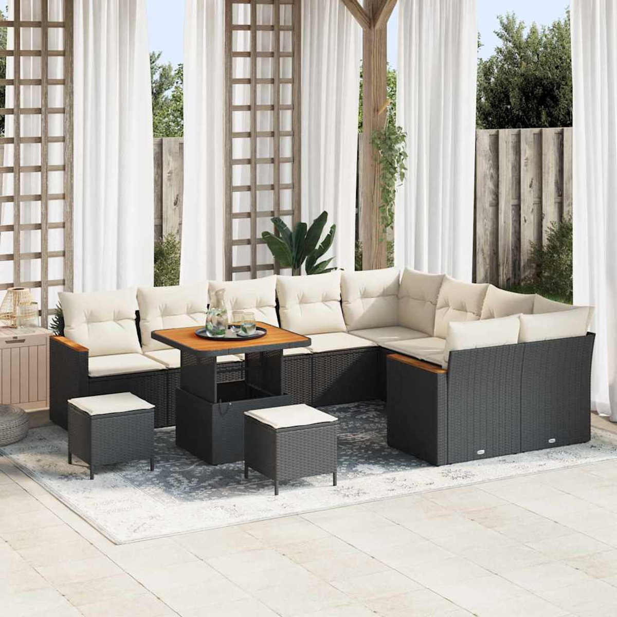 Outdoor-Terrassenset mit schwarzen Korbmöbeln, beigefarbenen Kissen und einem Holztisch auf einem gemusterten Teppich.