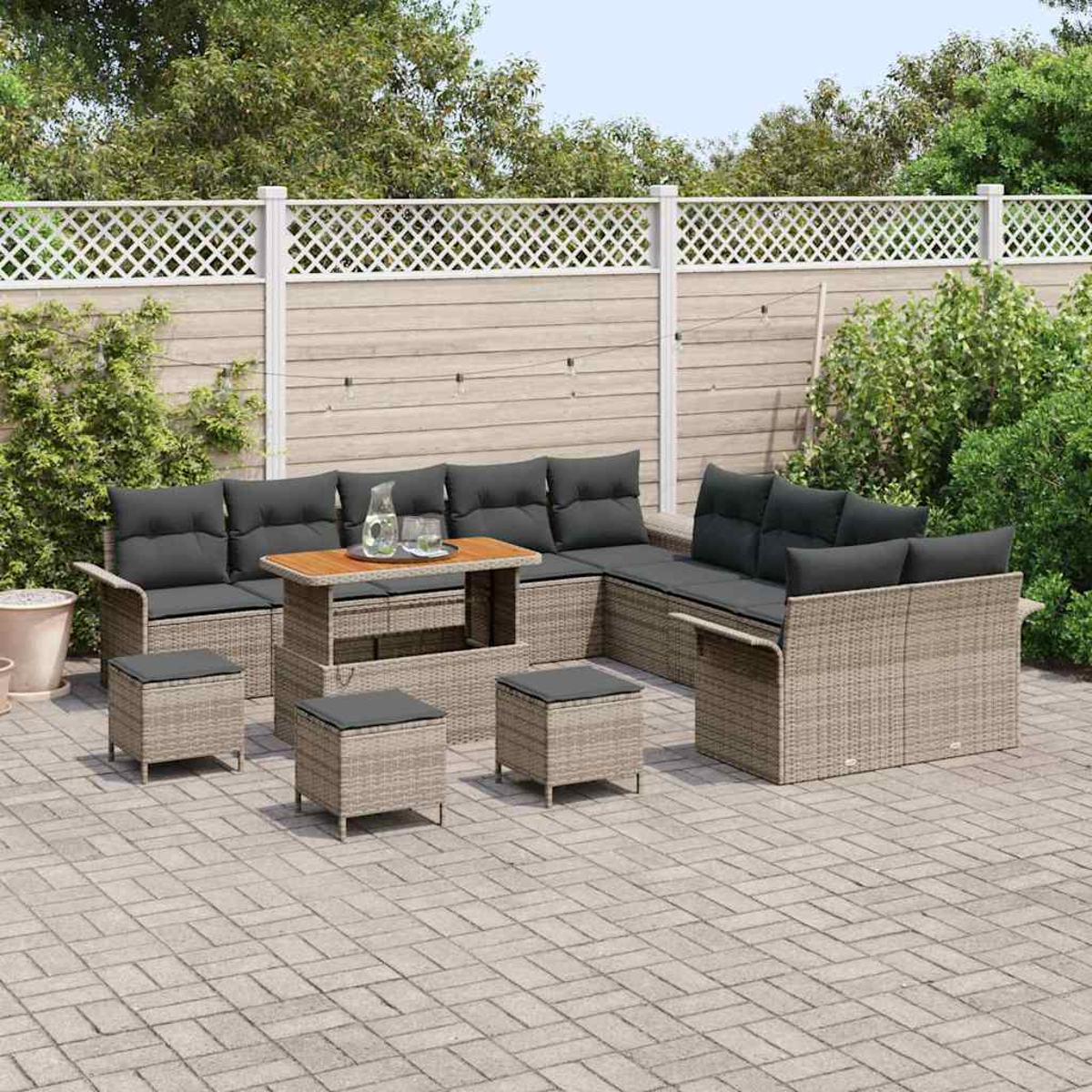 Garten-Rattansofa-Set mit Kissen, Tisch und Hockern auf einer Terrasse. Im Hintergrund ein Zaun und Grün.