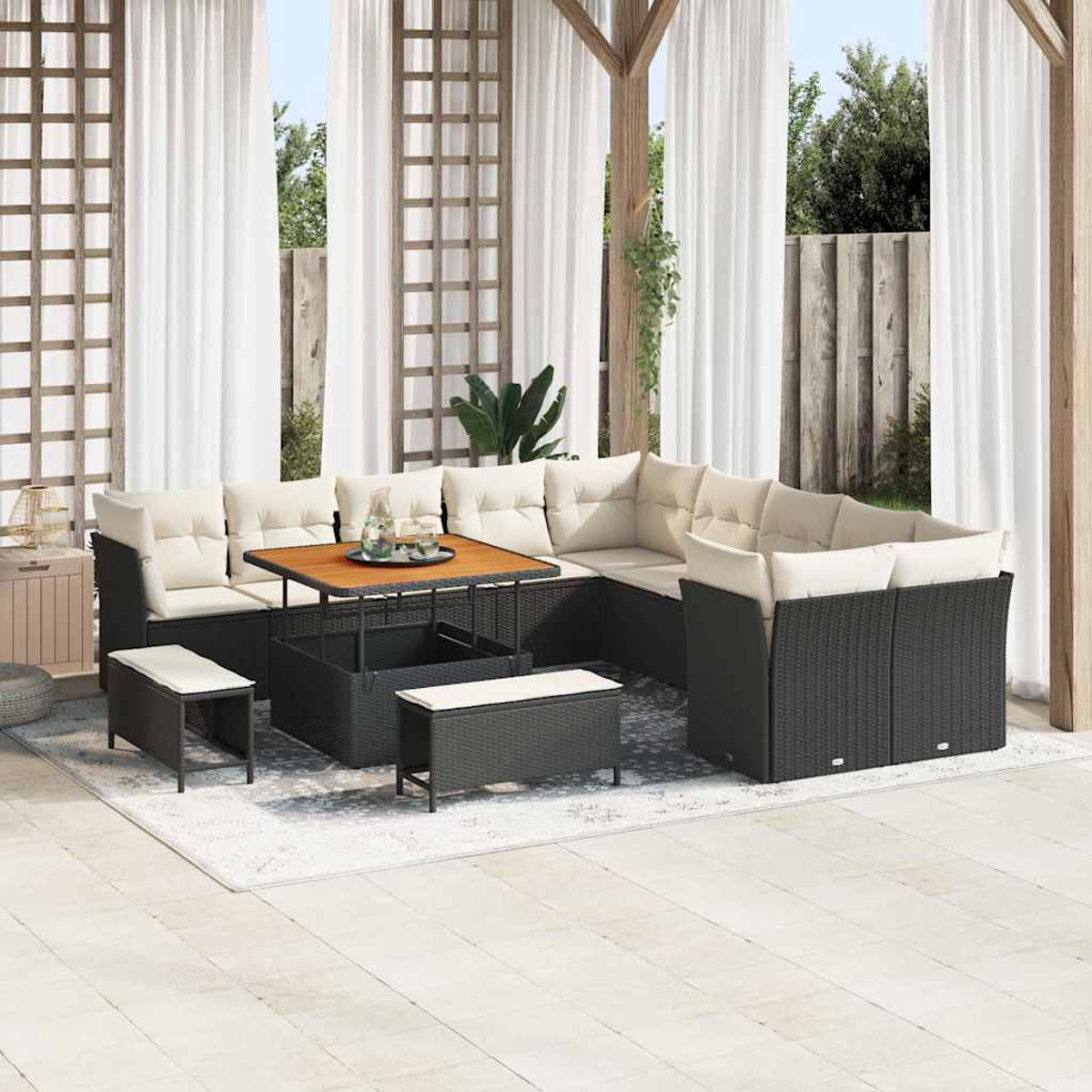 Ein Outdoor-Terrassen-Set mit schwarzen Korbmöbeln und cremefarbenen Kissen. Enthält ein Ecksofa, einen Tisch und Bänke, alles auf einem Teppich.