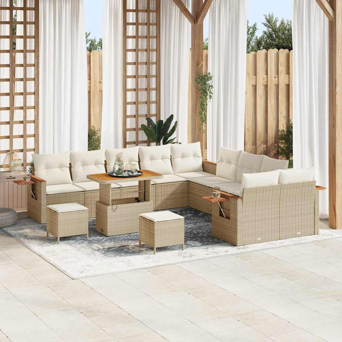 Set di mobili da patio: divani beige, tavolino e pouf su un tappeto. Tende bianche e struttura in legno sullo sfondo.
