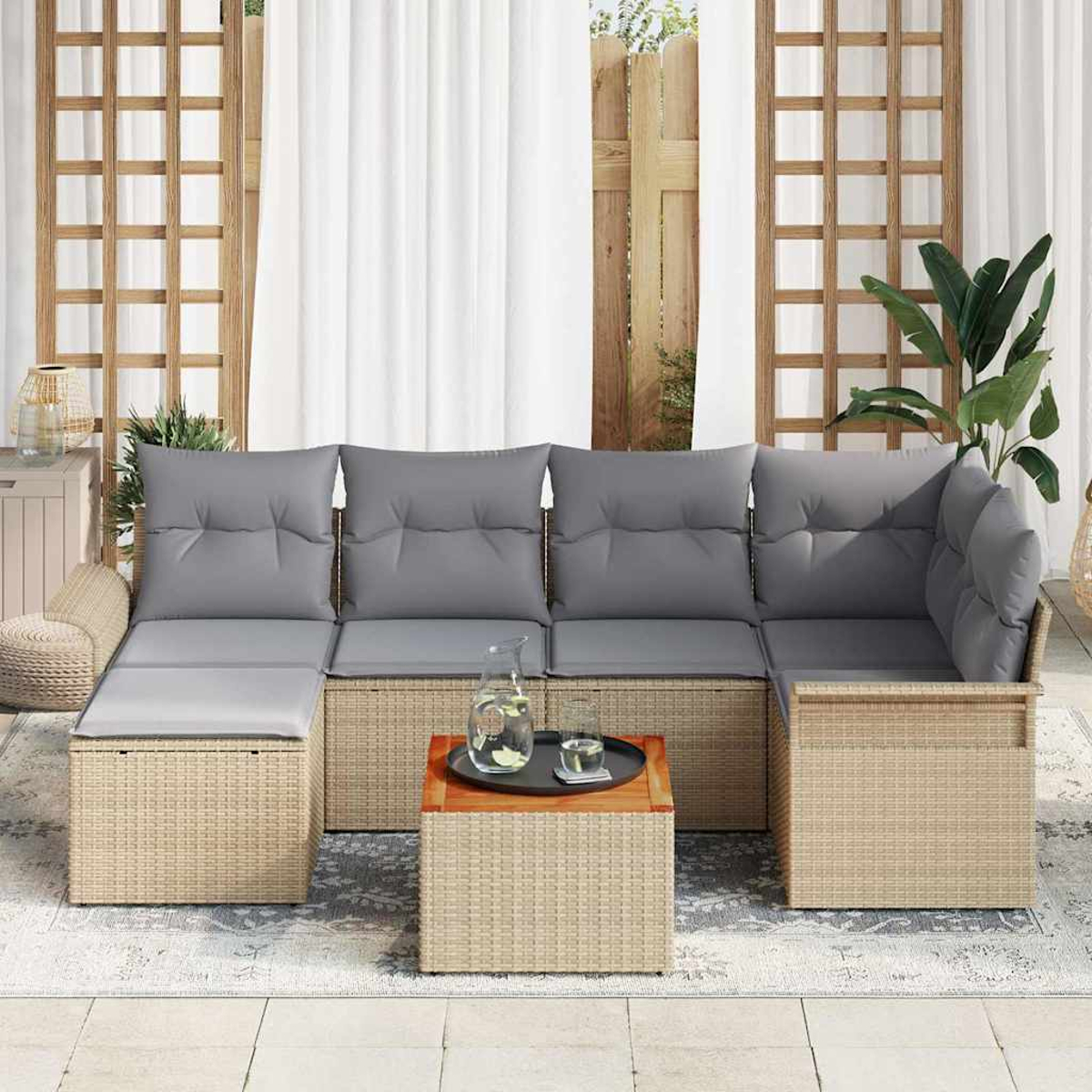 Outdoor-Korbsessel mit grauen Kissen. Kleiner Holztisch mit Tablett und Glas. Weiße Vorhänge und Holzgitter im Hintergrund.