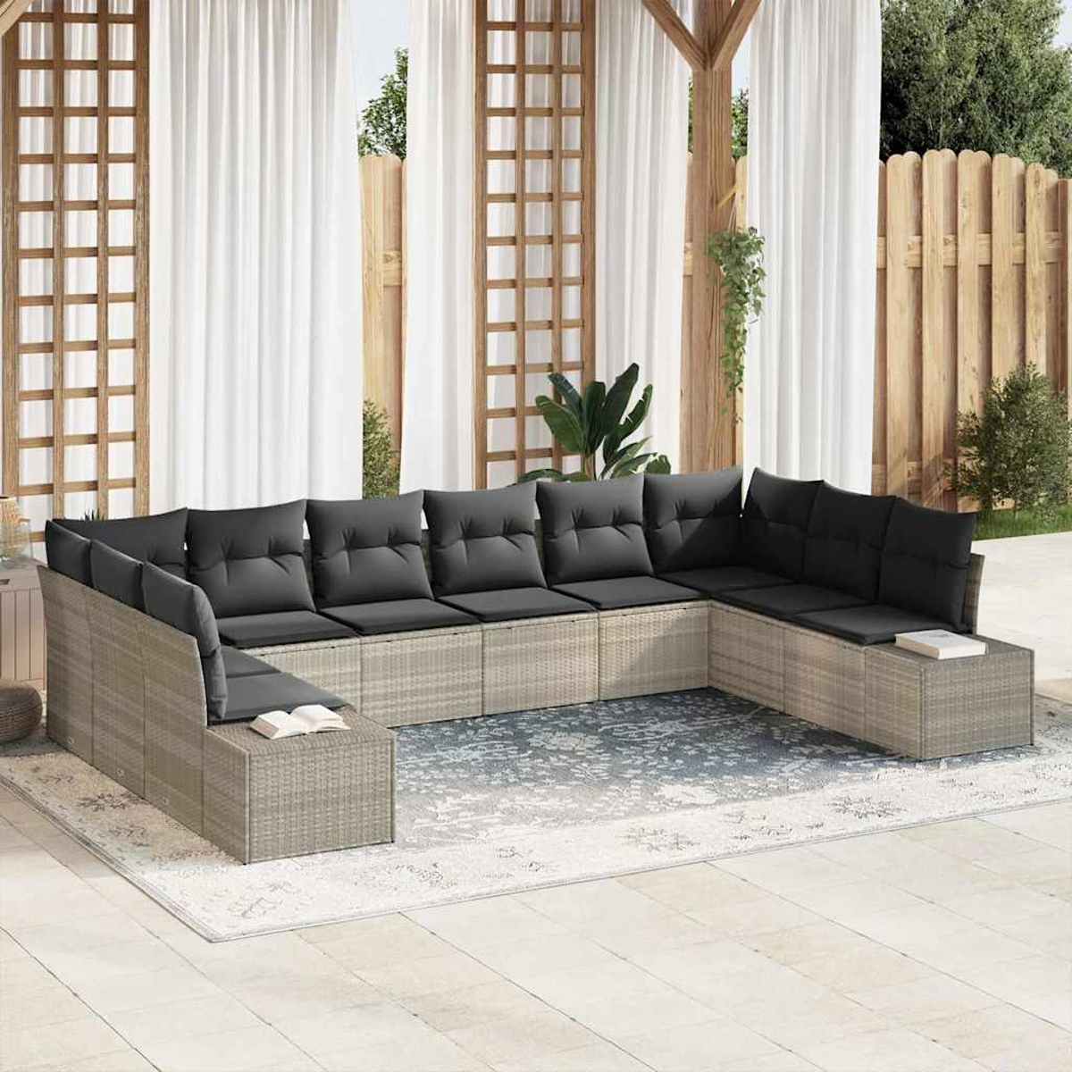 U-förmiges Sofa im Freien mit grauen Kissen. Es steht auf einem Teppich, umgeben von einer Terrasse. Weiße Vorhänge und Holzzaun im Hintergrund.