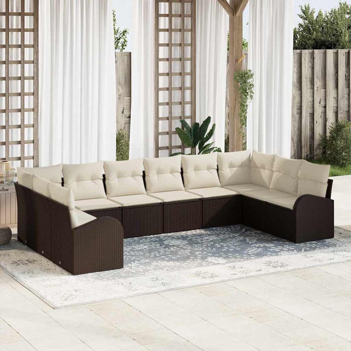 Ein Ecksofa im Freien mit cremefarbenen Kissen. Es steht auf einem Teppich, im Hintergrund weiße Vorhänge und Holzkonstruktionen.