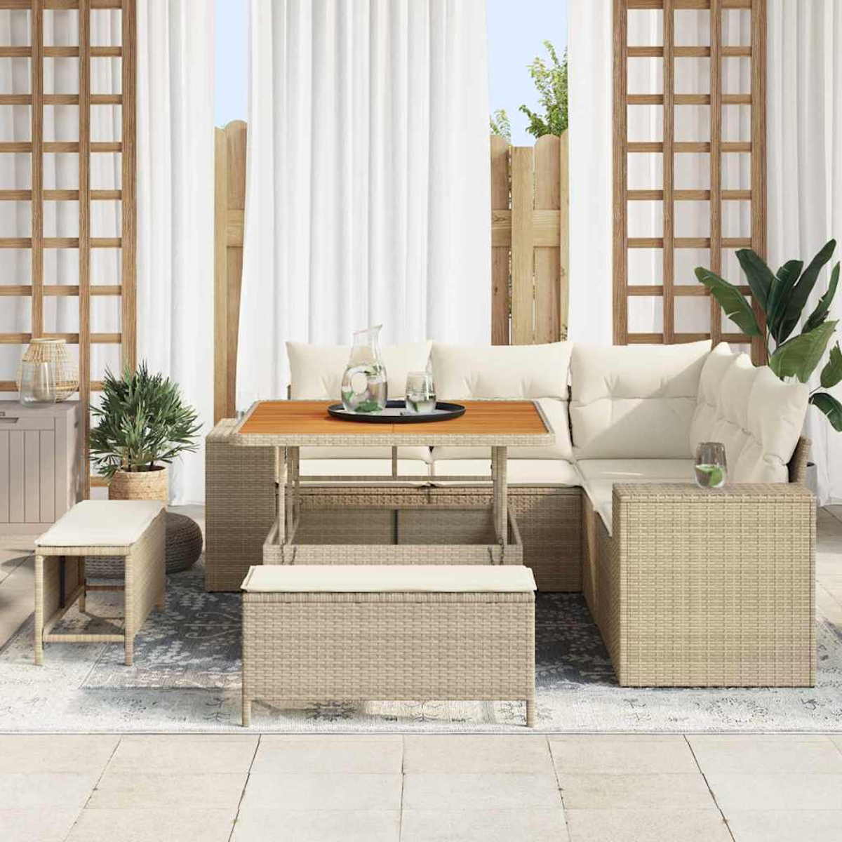 Terrassenset im Freien. Korbmöbel mit weißen Kissen. Weiße Vorhänge im Hintergrund. Pflanzen und eine Bank vervollständigen die Szene.