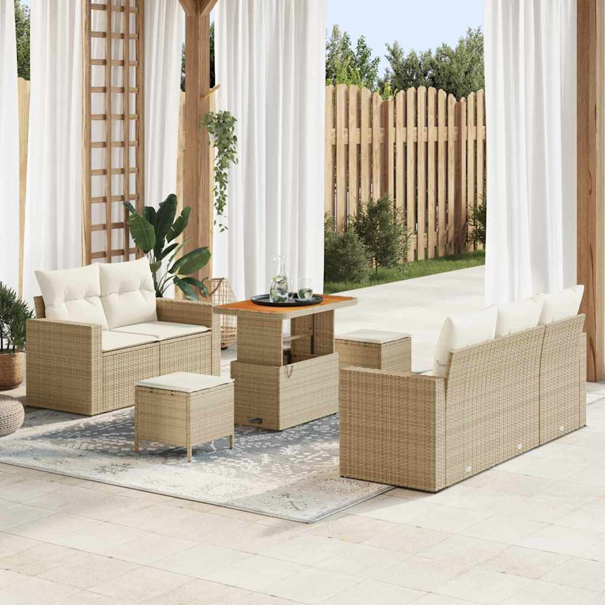 Terrassenmöbel-Set mit Sofa, zwei Stühlen, einem Tisch und einem Hocker. Weiße Vorhänge, Holzzaun und Pflanzen im Hintergrund.