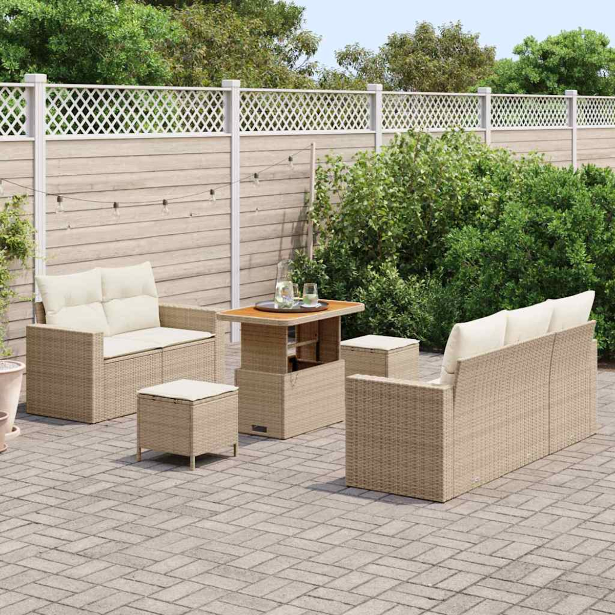 Gartenmöbel-Set aus Korbgeflecht auf einer Ziegel-Terrasse. Enthält Sofa, Sessel, Tisch und zwei Hocker, vor Holzzaun.