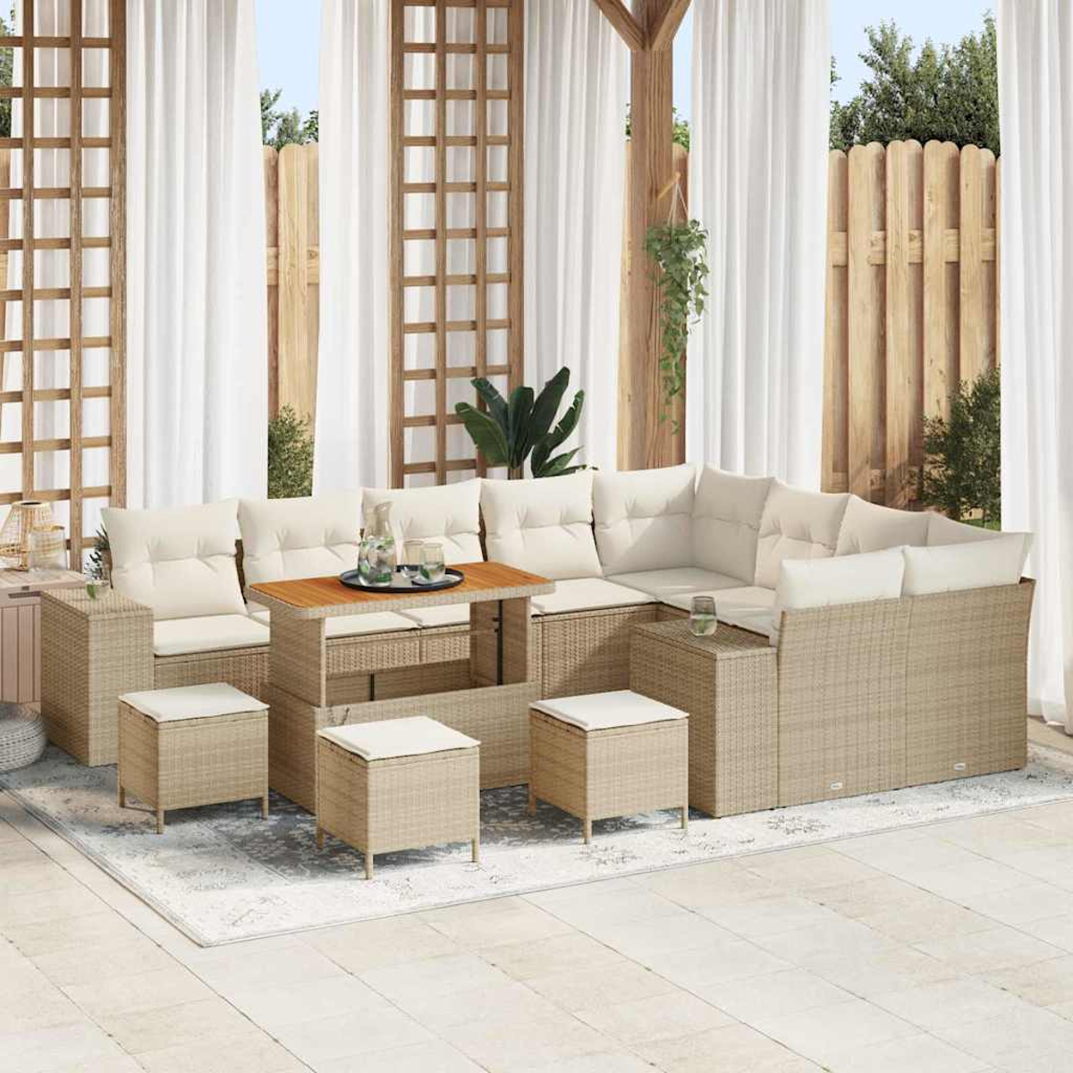 Outdoor-Rattanmöbel-Set auf einem Teppich. Enthält ein Sofa, Hocker und einen Tisch. Weiße Vorhänge und Holzgitter im Hintergrund.