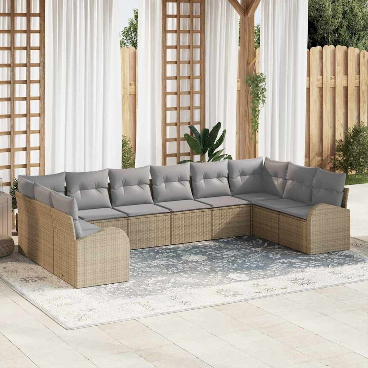 Ein Ecksofa im Freien mit grauen Kissen auf einem gemusterten Teppich. Weiße Vorhänge und Holzzaun sind im Hintergrund.