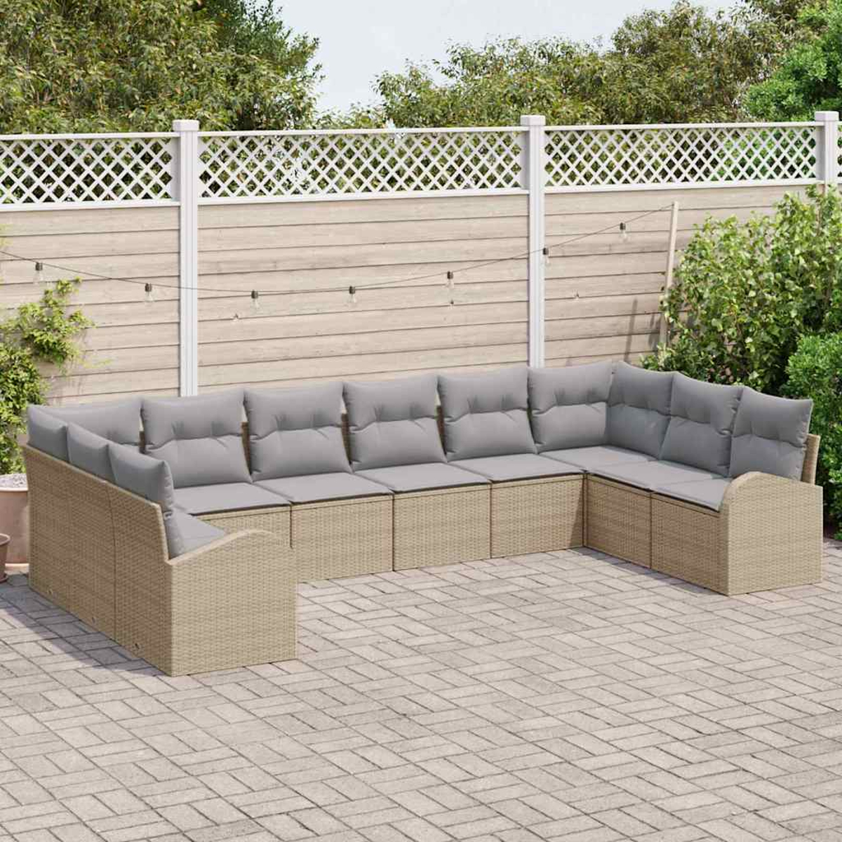 Ein Ecksofa mit grauen Kissen im Freien steht auf einer Terrasse. Ein weißer Gitterzaun und Blätter sind im Hintergrund.