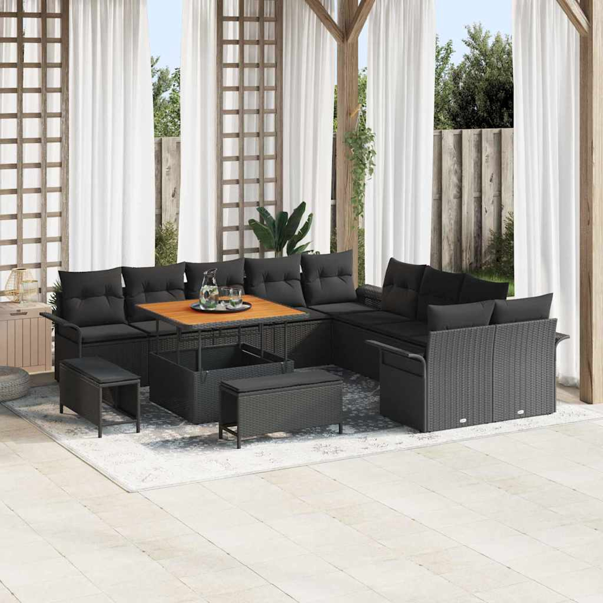 Terrassenset mit schwarzen Kissen, Holztisch und Bänken auf einem Teppich, mit weißen Vorhängen und Holzstruktur.